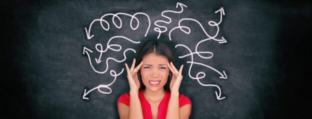 Confused woman confusion illustrated on blackboard with chalk drawing of arrows going everywhere around head showing indecision. Indecisive stressed Asian girl with headache panoramic banner.