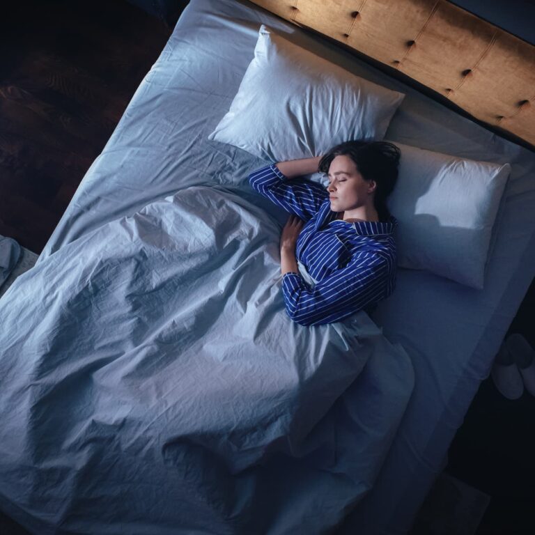 Top View of Beautiful Young Woman Sleeping Cozily on a Bed in Her Bedroom at Night. Comfortable Apartment with Sweet Girl Resting when Moonlight Shining Through Apartment Window. Top Down